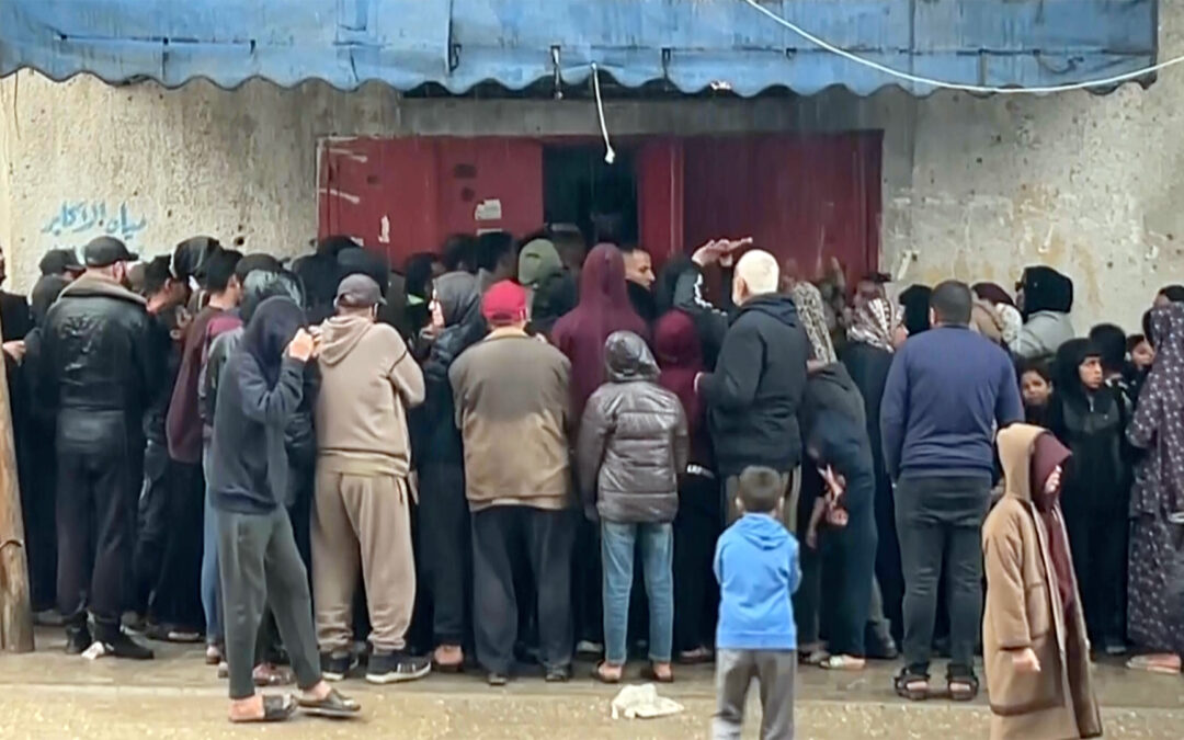 Palestinians queue for hours in pouring rain to get bread