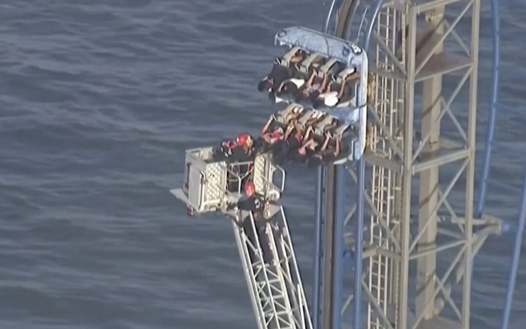 Firefighters work to free riders stuck atop a rollercoaster in Texas